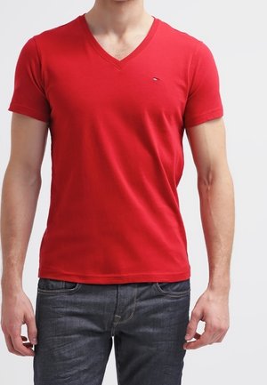 Rød bomulds t-shirt med V-hals og korte ærmer, der har en lille logo på brystet. Bæres med mørke jeans og viser et tætsiddende design.