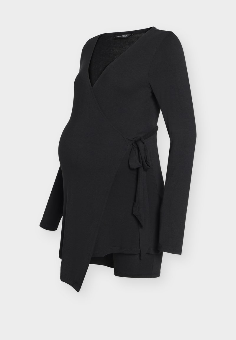 Haut de maternité noir à manches longues avec un lien sur le côté et un col en V, conçu pour le confort et le style pendant la grossesse.