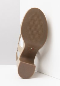Scarpa con tacco beige in pelle liscia. Suola in gomma antiscivolo con un motivo testurizzato. Logo stampato all'interno. Design curvo ed elegante.