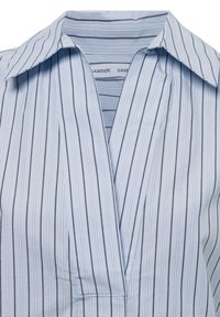  Lichtblauw shirt met dunne verticale zwarte en witte strepen en een open kraag die het merklabel binnenin laat zien.