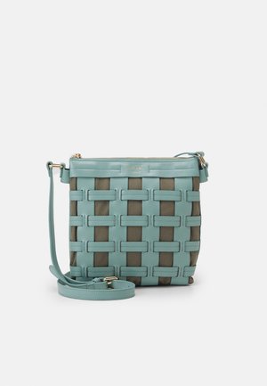 Lyseblå vævet crossover taske med læderstropper, lynlåslukning og en kontrastfarvet mørkere stofbund med rektangulære mønstre.