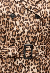 Trench-coat à imprimé léopard avec des boutons noirs et une ceinture assortie en tissu fixée par une boucle rectangulaire noire.