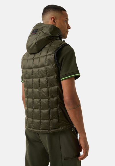 Olivgrüner Kapuzenweste, gestepptes Design, leichtes Material, seitliche Reißverschlüsse, kombiniert mit einem dunkelgrünen Hemd mit grünen Akzenten.