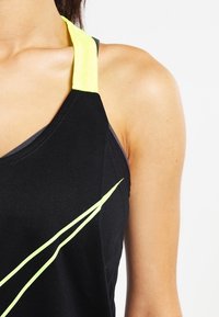 Zwarte sporttanktop met een gele accenten op de schouder en een groen ontwerpelement op de voorkant. Gemaakt van een rekbare, gladde stof.