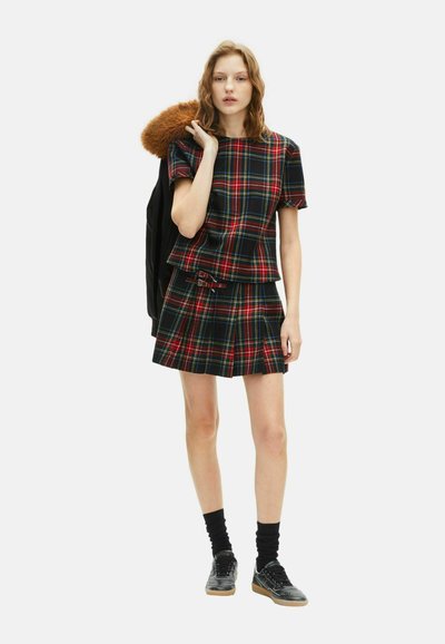 Sorte og røde plaid-top med en matchende nederdel, der har et tætsiddende design, metallisk spænde detalje og er parret med sneakers og sokker.