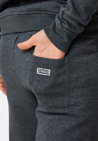 Mörkgrå sweatpants med en mjuk textur, elastisk midja och bakficka med en vit denim-varumärkestagg.