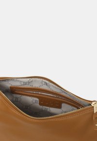Borsa in pelle marrone con zip dorata, dotata di un interno grigio a motivi e una tasca. Etichetta del marchio in rilievo visibile all'interno.
