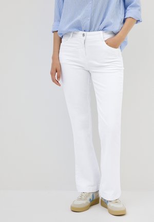 Jeans flare in denim bianco con un classico design a cinque tasche, chiusura anteriore con bottone e texture morbida. Abbinati a sneakers color crema.