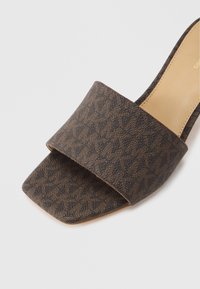 Sandalia de diapositiva marrón con parte superior de tela estampada, punta cuadrada y plantilla de cuero suave. Diseño minimalista con talón abierto.