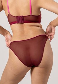 Röd genomskinlig mesh-bh och matchande trosor med rosa detaljer. BH:n har ett hakhakhäng och justerbara band, vilket framhäver en slät textur.