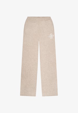 Beige weite Hosen aus weichem Stoff, mit einer strukturierten Oberfläche und einem gestickten Emblem auf der Vorderseite.