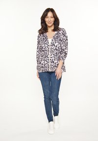 Letvægts zip-up jakke med pink og sort leopardprint, kombineret med mørkeblå denimjeans og hvide sneakers. Glat tekstur, afslappet pasform.