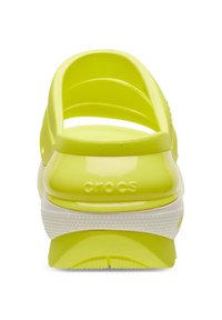 Gele plastic Crocs met een open achterkant, voorzien van meerdere sleuven voor ventilatie en een contrasterende witte zool met een getextureerd patroon.
