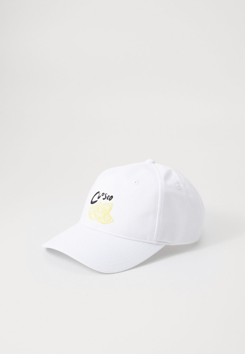Vit basebollkeps med svart text och broderat gult citrusfruktstycke på framsidan, med böjd skärm och justerbar baksida.