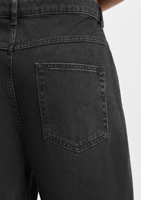 Mustat farkut slim fit -mallilla, joissa on yksi takatasku, perinteinen ommel ja sileä pinta.