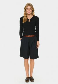 Black, ribbed long-sleeve top with a keyhole detail, paired with loose-fit, knee-length navy shorts. Brown belt and dark loafers complete the outfit.