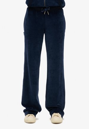 Navy fluwelen sweatpants met een losse pasvorm, voorzien van een elastische tailleband en trekkoord, die passen bij beige schoeisel.