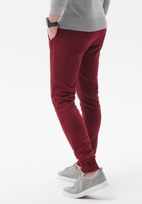 Bordeaux joggingbroek met een tapered fit, zijzakken en geribbelde manchetten; gecombineerd met grijze sneakers, met een gladde textuur en een minimaal design.