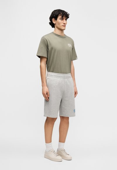 Πράσινο ελιάς βαμβακερό T-shirt με στρογγυλή λαιμόκοψη, σε συνδυασμό με γκρι βαμβακερά σορτς με ελαστική μέση και λεπτομέρεια με λογότυπο σε ανοιχτό μπλε.