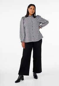Black and white gingham button-up top with puffed sleeves, round neckline, and elastic cuffs, paired with wide-leg black pants and ankle boots.