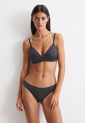 Reggiseno nero morbido e elastico con spalline sottili, scollatura profonda e culotte abbinate. Texture liscia, senza motivi o decorazioni visibili.