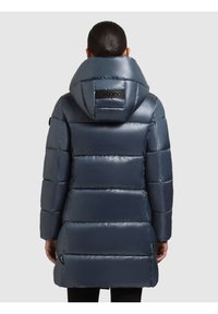 Padinta pūkinė striukė blizgia tamsiai mėlyna spalva, su dideliu gaubtu, horizontaliomis siūlėmis ir logotipo detale ties kaklu. Šonuose yra užtrauktukų kišenės.