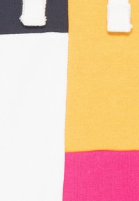 Färgglad tyg med vertikala ränder i vitt, marinblått, gult och rosa, med en slät textur och kontrasterande sömnadsdetaljer.
