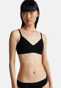 Zwarte bralette van zacht stof met een V-halsontwerp, dunne verstelbare bandjes en een naadloze afwerking. Geschikt voor dagelijks gebruik.