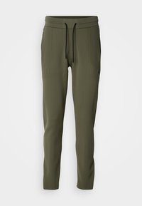 Pantalones jogger verde oliva con textura acanalada, cintura elástica y cordón negro. Cuenta con bolsillos laterales y puños ajustados.