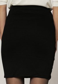 Svart figursydd kjol i stickad kvalitet, med en mjuk textur och en subtil stretch, som har en ren silhuett och inga synliga dekorationer.