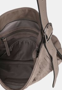 Vaaleanruskea nahkainen olkalaukku, jossa on sisällä vetoketjutasku, kangasvuori ja mokkaiset yksityiskohdat. Ulkopinnassa huomattavaa tekstuuria.