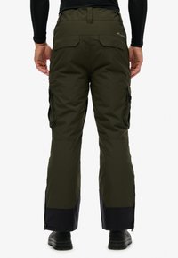 Olijfgroene skibroek met cargozakken, taps toelopende pijpen, ritsen aan de enkels en een zwarte onderste zoom. Glad stof met een matte afwerking.