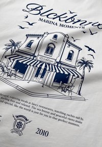 Wit stoffen grafiek met een blauwe lijntekening van een strandrestaurant met een gestreepte luifel, palmbomen en tekst over "Marina Moments."