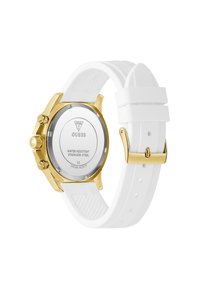Montre en acier inoxydable doré avec un bracelet en silicone blanc, présentant une surface texturée et un fond de boîtier en argent avec des détails imprimés.