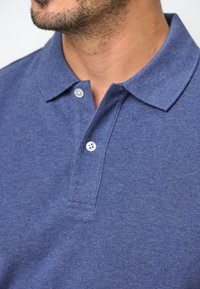 Mans mörkblå polo skjorta med strukturerad tyg, med krage och två knappar vid kragen.