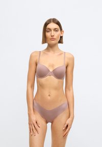 Svetlohnedá, hladká podprsenka s kostícami a nastaviteľnými ramienkami, doplnená o zladené bikinové nohavičky s nízkym pásom. Oba kúsky majú minimalistický dizajn.
