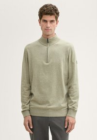 Hellgrüner, langärmeliger Pullover mit hohem Kragen und einem Viertelreißverschluss. Weicher Stoff mit gerippten Bündchen und Saum. Minimalistisches Design.