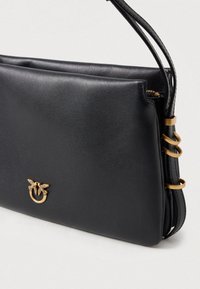 Černá kožená kabelka s elegantním designem, zlaté detaily ve tvaru včely a kulaté kovové akcenty na straně. Hladká textura, minimalistický tvar.