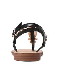 Zwarte sandalen met een glad leren bovenwerk, dunne enkelband en een lichtbruine zool. Heeft decoratieve accenten aan de achterkant.