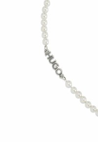 Collier de perles avec des perles blanches rondes et un accent métallique "HUGO". Le design comprend un fermoir pour un maintien sécurisé.