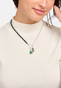 Schwarze Perlenkette mit silberner Kette, versehen mit einem grünen Weihnachtsbaum-Anhänger und einem Schneemann-Anhänger mit bunten Akzenten.