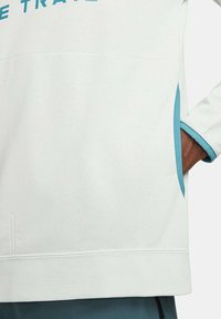 Helles graues Sweatshirt mit türkisfarbenen Akzenten. Verfügt über einen Rundhalsausschnitt, eine Seitentasche und einen strukturierten Stoff. Glatte und gemütliche Haptik.