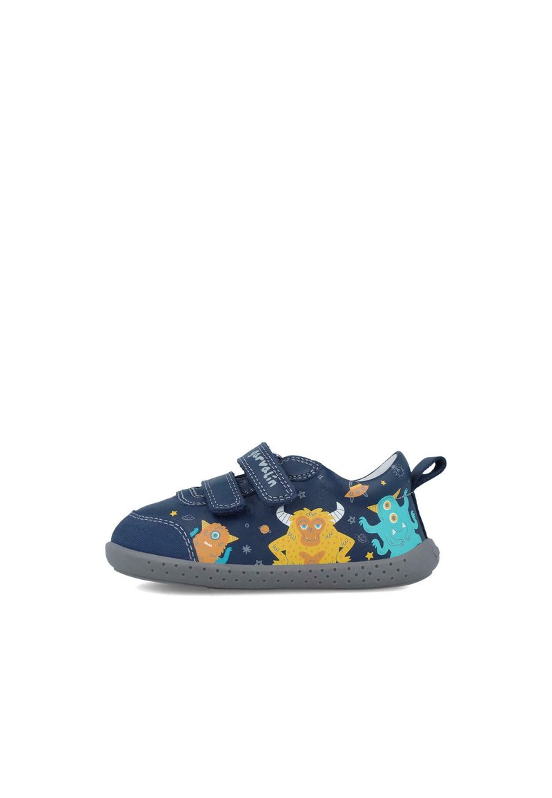 Zapato infantil azul marino con dos correas de velcro, que presenta gráficos de monstruos coloridos, suela de goma gris y un tirador en el talón reforzado.