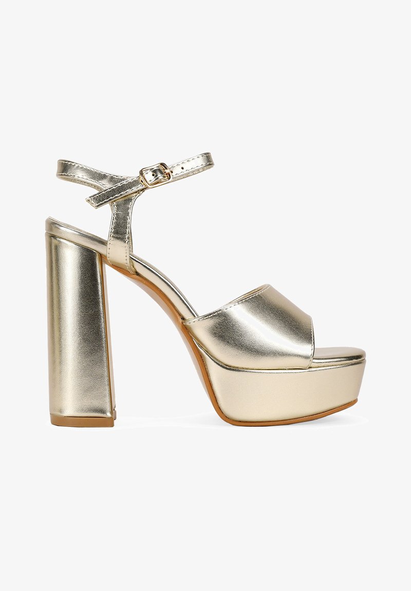 Metallic gold platform sandals with a wide heel, open toe, and ankle strap. Smooth texture with a glossy finish and buckle detail.
