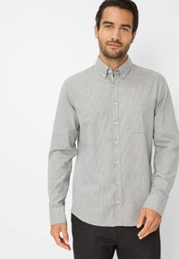 Grijs en wit geblokt overhemd met kraag, borstzak en lange mouwen, gecombineerd met donkere broek. Gelaagd stof.