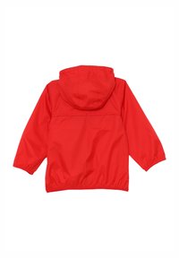 Giacca impermeabile rossa con cappuccio. Presenta polsini e vita elasticizzati. Texture liscia, design semplice, colore uniforme. Visto da dietro.