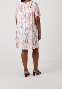 Sukienka z krótkim rękawem z lekkiego, przezroczystego materiału z wielokolorowym, abstrakcyjnym wzorem. Ma luźny fason i sięga tuż nad kolano.