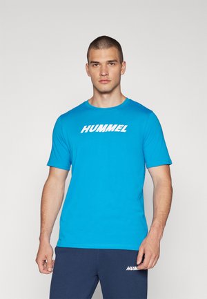 Himmelblaues T-Shirt mit kurzen Ärmeln aus weichem Stoff und Rundhalsausschnitt. Mit einem auffälligen weißen "HUMMEL"-Logo über der Brust.