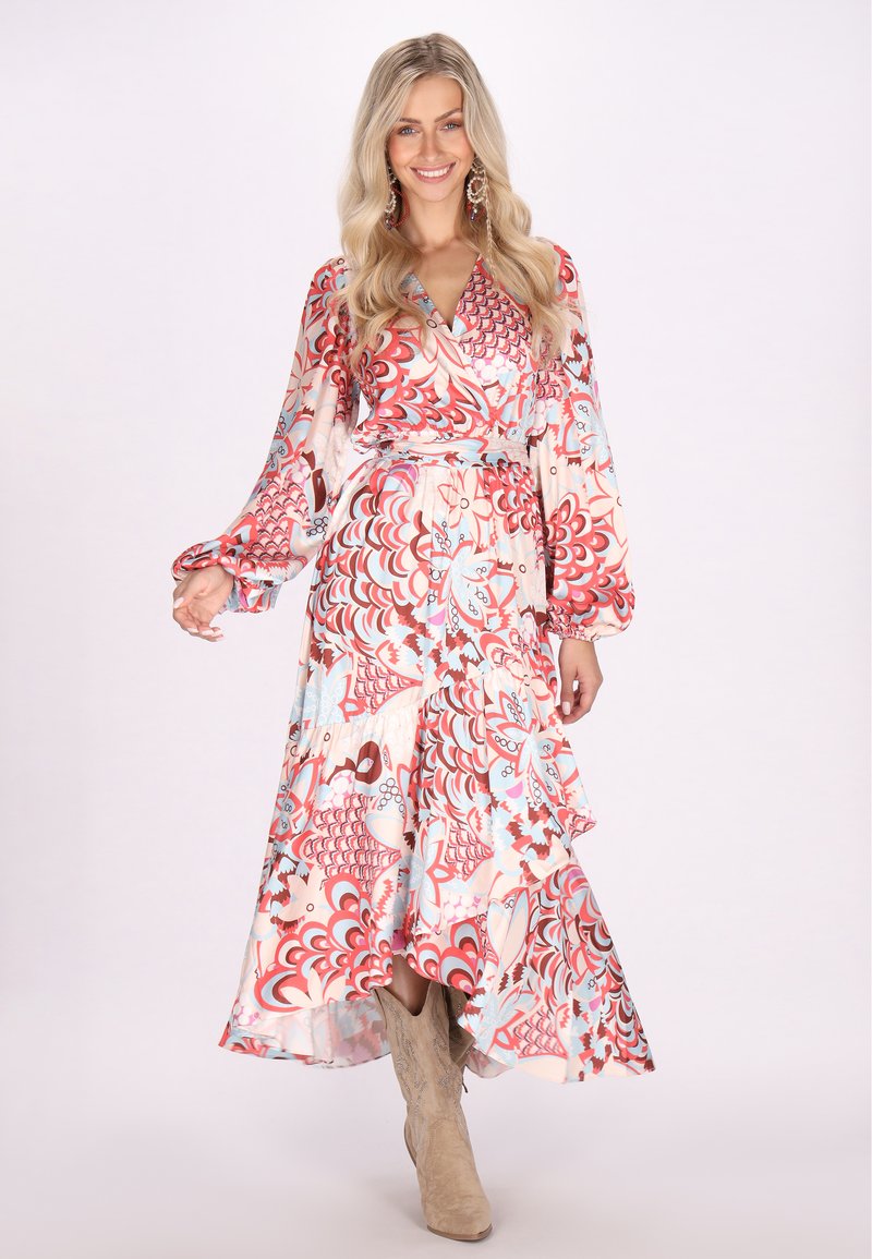 Rochie florală în stil wrap cu mâneci lungi, în culori pastelate, având un amestec de modele roșii, albastre și crem. Asortată cu bocanci bej până la gleznă.