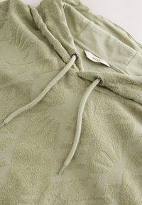 Felpa con cappuccio verde chiaro con motivo strutturato, cappuccio con coulisse e tessuto morbido. Etichetta con la scritta "NEXT." Dettagli a coste come accento.